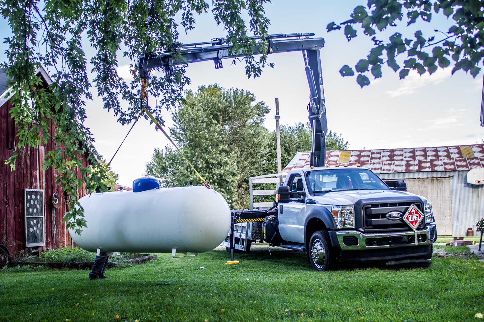 crane holding white tank in grass