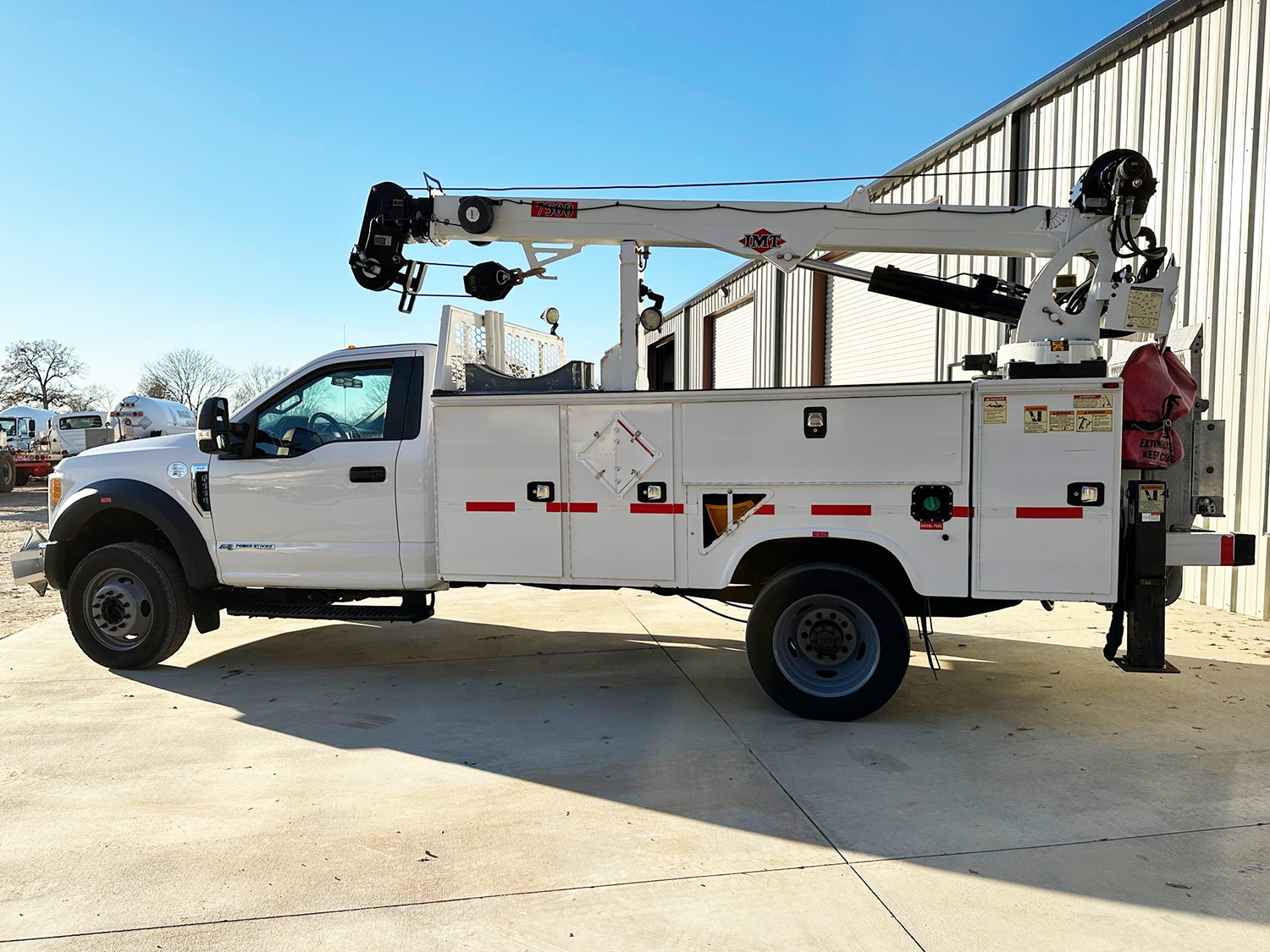 A white Fisk utility truck with a crane on top of it