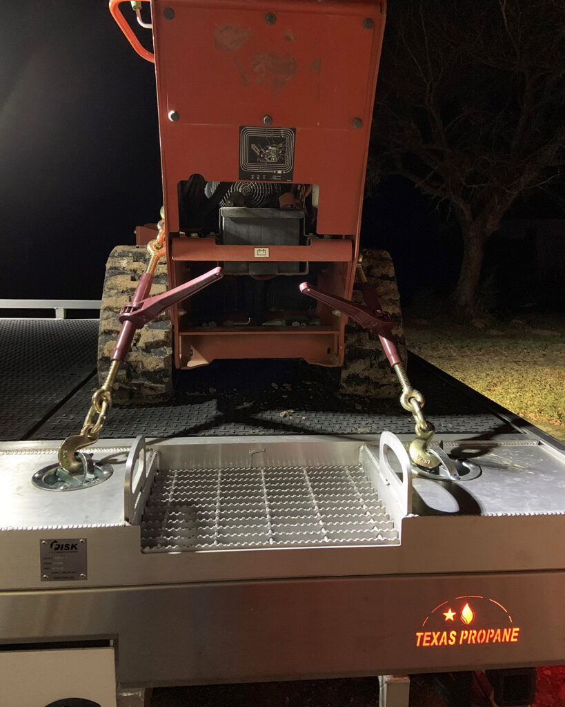 Image contains a trench digger on the back of a Fisk propane truck, strapped down with D rings. A backlit fender says Texas Propane.