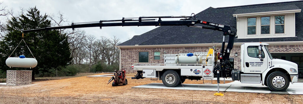 Image contains a propane truck extending the knuckle boom to the back to set a tank.