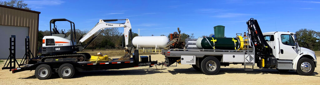 Image contains propane boom truck carrying propane tanks and trencher on the bed with a trailer.